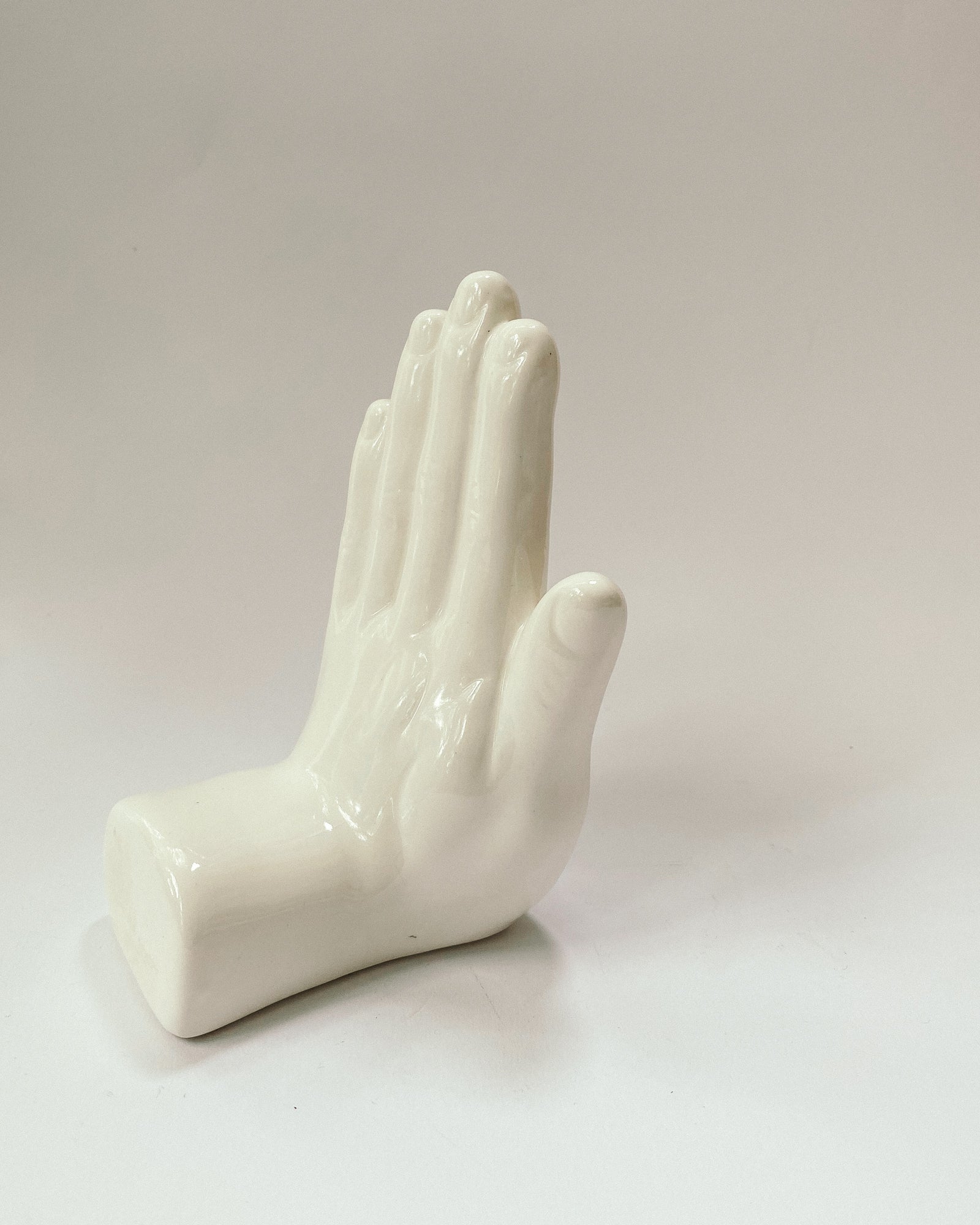 weiße Buchstütze in Form einer Hand