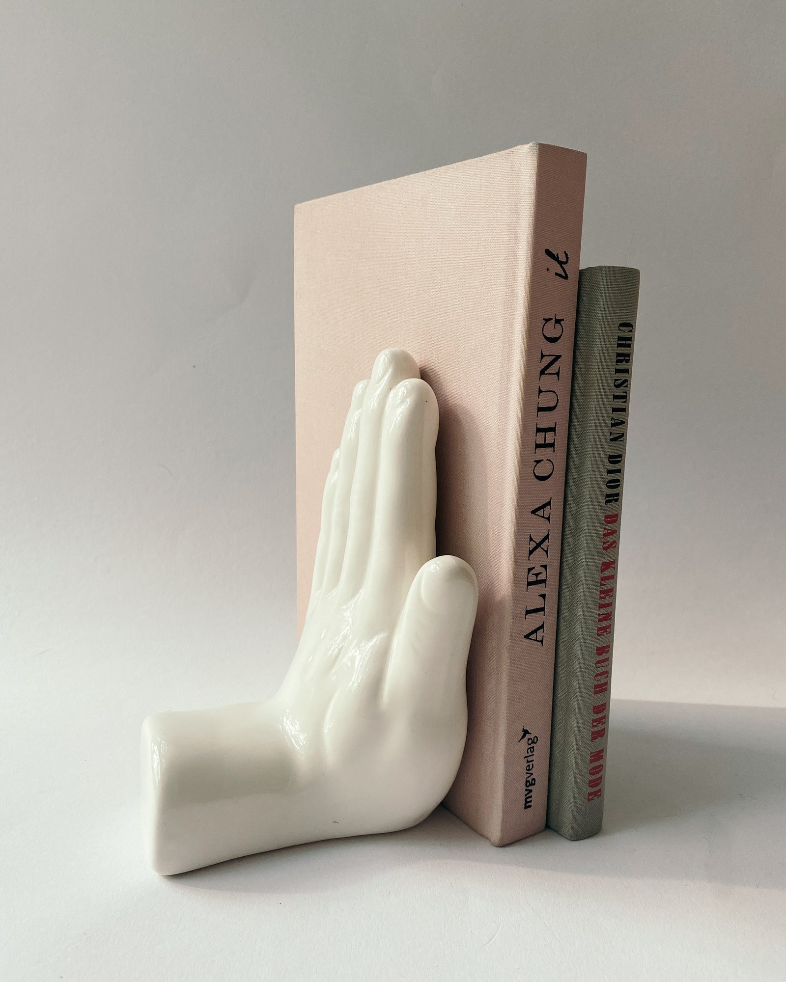 weiße Buchstütze in Form einer Hand